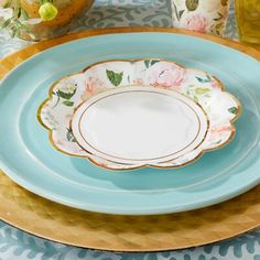 a blue and white plate sitting on top of a table next to a vase with flowers