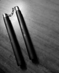 black and white photo of two lighters on table with chain attached to the ends