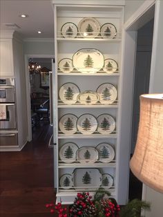 the china cabinet is decorated with plates and pine trees