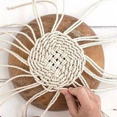 a person is tying rope on top of a piece of wood with a circular object in the background