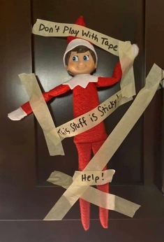 an elf is holding up some paper taped to his face with words on it, and he