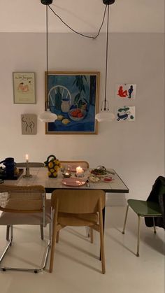 a dining room table and chairs with artwork on the wall