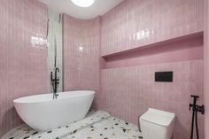 a bathroom with pink tiles and a white bathtub in the middle of the room