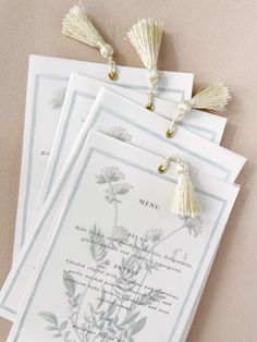 four cards with tassels on them sitting next to each other