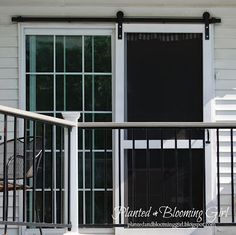 a balcony with sliding glass doors and an iron railing on the side of a house