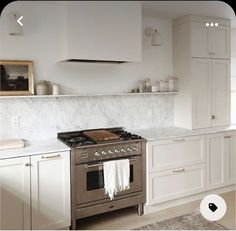 a stove top oven sitting inside of a kitchen next to white cabinets and counter tops