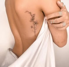 a woman with a flower tattoo on her upper arm and shoulder, wrapped in a white cloth