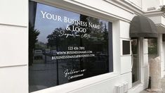 a storefront with business name and logo on it's glass window, in front of a white building