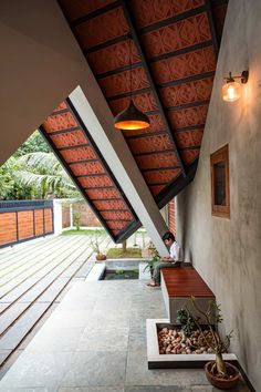 a man sitting on a bench under a roof next to a planter filled with plants