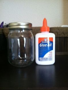 a bottle of glue sitting on top of a table next to a glass jar filled with glue