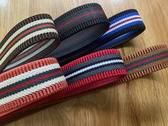 four different colored striped ties laying on top of a wooden table next to each other