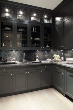 a kitchen filled with lots of black cabinets and counter top space next to a sink