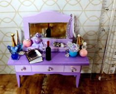 a purple vanity with a mirror and jewelry on it next to a measuring ruler,