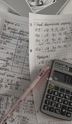 a calculator sitting on top of papers with writing and numbers written on them