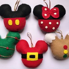 four mickey mouse christmas ornaments hanging from hooks on a white surface with red, green and yellow bows