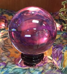 a purple glass ball sitting on top of a bed