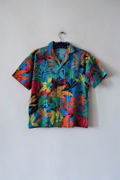 Stunning Vintage Hawaiian style shirt from the 1980s. Comfortable cotton fabric with an amazing tropical jungle print featuring elephants and exotic plants. Straight cut, short lapel collar, short sleeves. Button down. Unisex. Made in Italy! Wear oversized and combine with Bermudas and sandals. BRAND: Marc Aurel ERA: 1980s COLOR: Azure blue, turquoise, green, raspberry, orange, yellow, brown, black FABRIC: 100% cotton SIZE: Vintage size S, fits best men's size S or woman's size M (or S for a mor Cheap Green Hawaiian Shirt, Cheap Retro Green Hawaiian Shirt, Tropical Collared Camp Shirt With Palm Tree Print, Tropical Palm Tree Print Collared Camp Shirt, Multicolor Cotton Hawaiian Shirt With Hibiscus Print, Tropical Cotton Hawaiian Shirt With Hibiscus Print, Multicolor Collared Shirt With Tropical Print, Multicolor Tropical Print Shirt With Camp Collar, Multicolor Camp Shirt With Hibiscus Print And Camp Collar