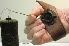 a hand holding a piece of wire and a spool of thread