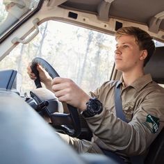 a man sitting in the driver's seat of a truck with his hands on the steering wheel