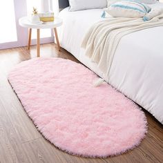 a pink rug on the floor next to a bed