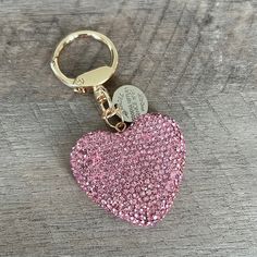 a pink heart shaped keychain on a wooden surface