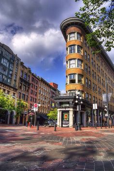 an old building on the corner of a street in front of other buildings and trees