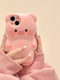 a woman holding up a pink pig phone case