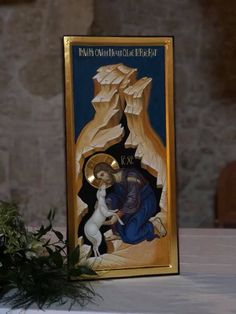 the icon is on display next to a potted plant in front of an old stone wall