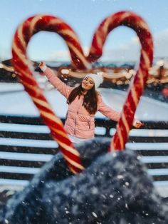 two candy canes in the shape of a heart and a woman standing next to them