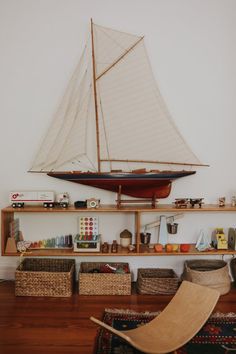 a toy sailboat sitting on top of a wooden shelf next to baskets and toys