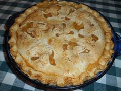 a pie sitting on top of a checkered tablecloth covered table with blue dishes