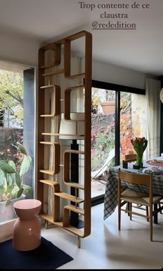 a living room filled with furniture next to a large glass window covered in plants and flowers