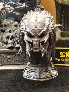 a statue of a demon head on display in a store window with other skulls behind it