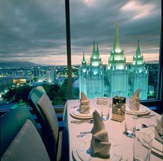 a table set with place settings in front of a view of the city at night