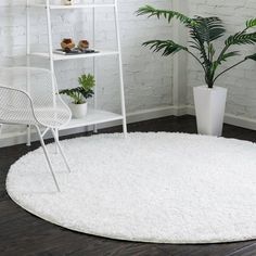 a white rug in the corner of a room with a chair and potted plant