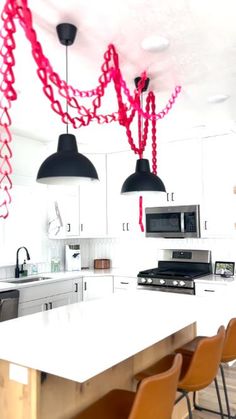 the kitchen is decorated with red streamers and black pendant lights hanging from the ceiling