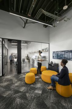 two people are sitting in an office with yellow chairs and black accents on the walls