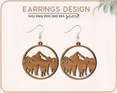 the earrings are made from wood and have mountains on them, with pine trees in the middle