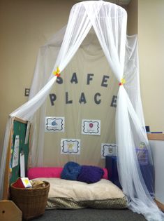 a bed with mosquito netting over it in an office cubicle area that reads safe place