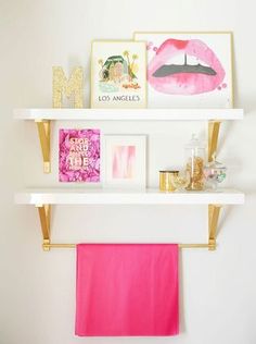 two white shelves with pink towels and pictures on them, one is hanging from the wall