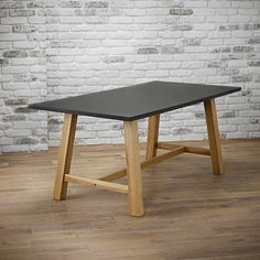 a black table sitting on top of a wooden floor next to a white brick wall