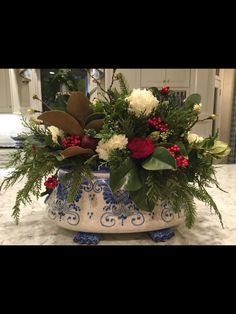 a blue and white vase filled with flowers on top of a marble counter topped with greenery