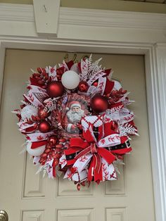 a red and white christmas wreath on the front door with santa's face in it