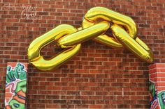 a large gold chain hanging from the side of a brick building next to graffiti covered walls