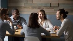 four people sitting at a table talking to each other