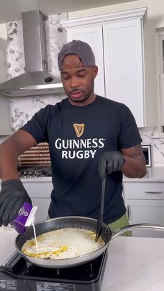 a man standing in front of a frying pan filled with food on top of a stove