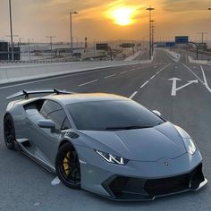 a grey sports car parked on the side of an empty highway at sunset or dawn