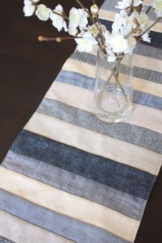 a vase filled with flowers sitting on top of a table next to a striped runner