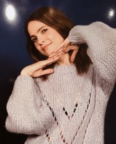 a woman wearing a white sweater posing for the camera