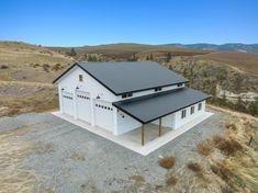 an aerial view of a two story white building with a metal roof and black shingles